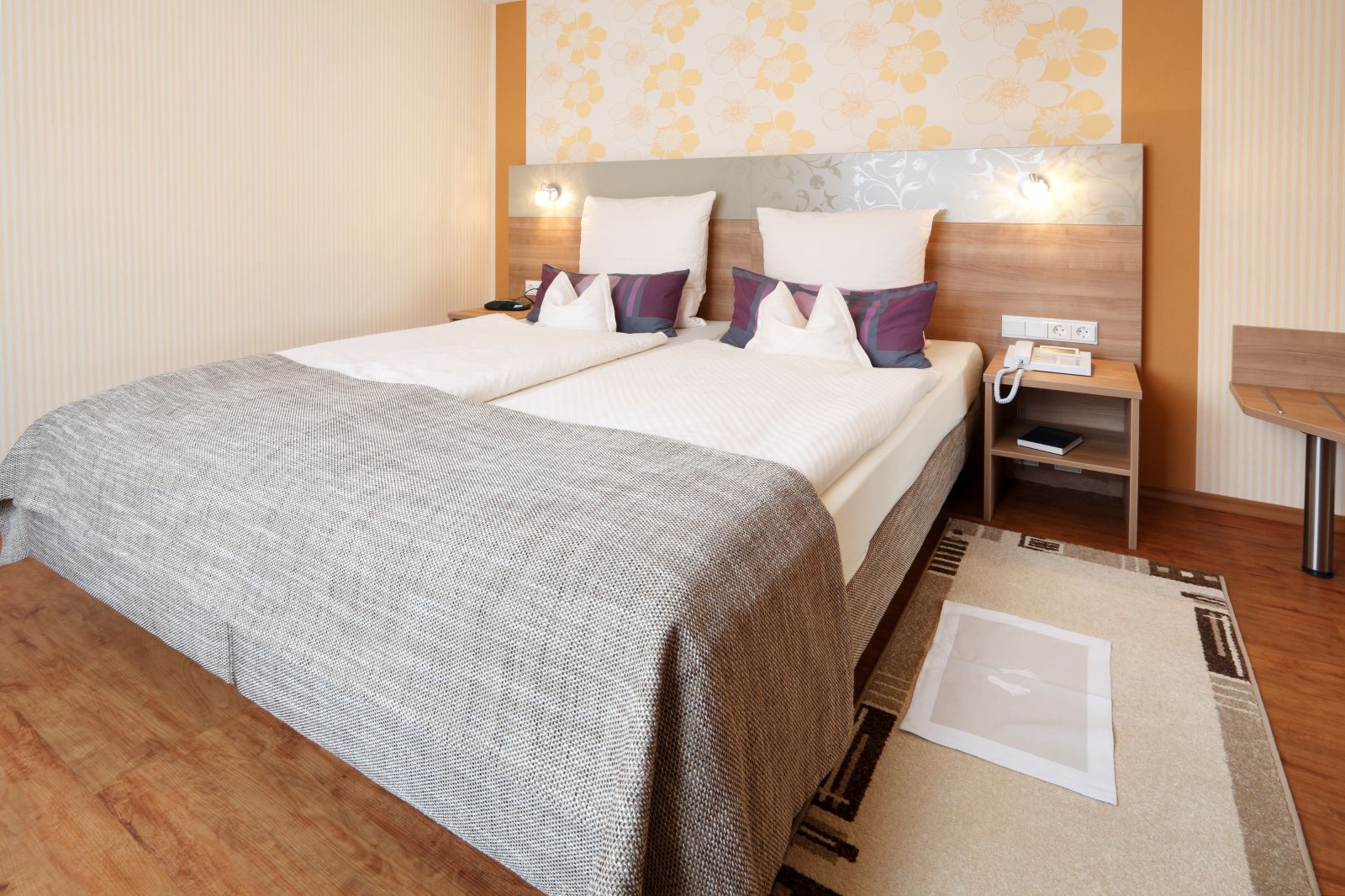 Gemütliches Schlafzimmer der Suite mit Doppelbett, Nachttisch und dekorativer Wandgestaltung